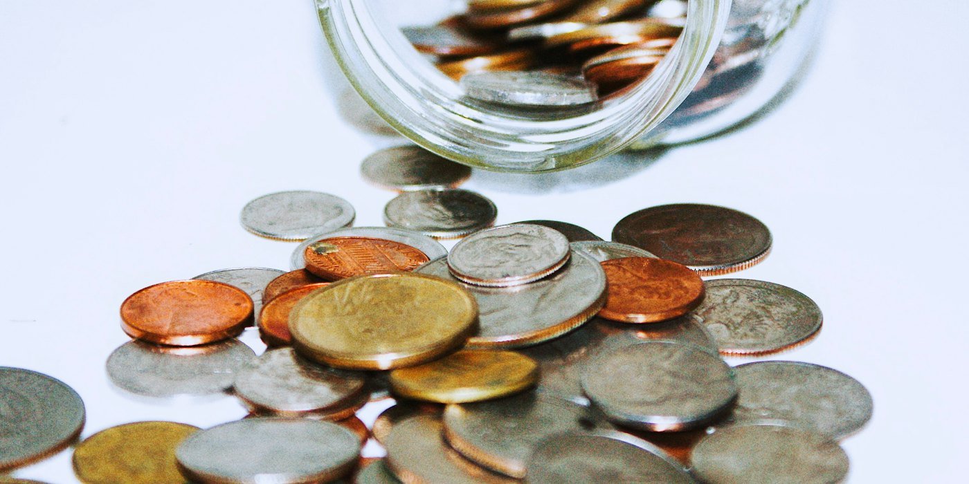 Frasco de vidrio transparente con monedas — Ahorrar en efectivo o en el banco: pros y contras