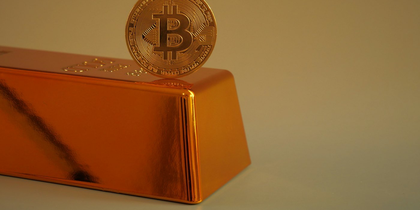 Moneda de Bitcoin descansando sobre un lingote de oro — Altcoins: por qué la mayoría desaparece