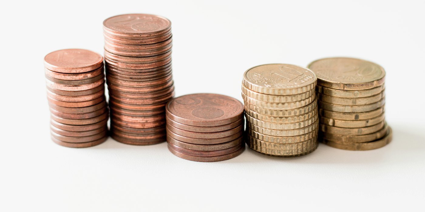 Monedas redondas apiladas de color dorado sobre superficie blanca — Bonos corporativos y de alto rendimiento