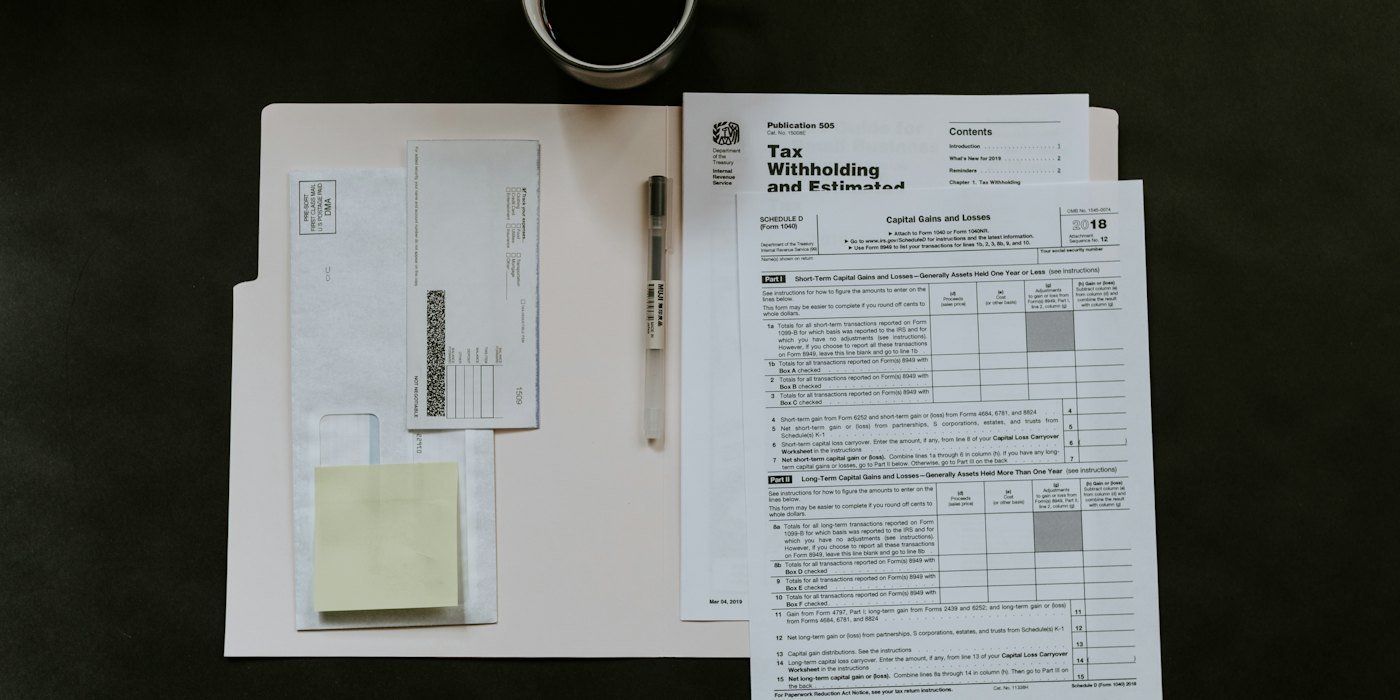 Formularios de impuestos, un bolígrafo y una taza de café sobre un escritorio oscuro — Borrador y Renta Web: cómo usarlos
