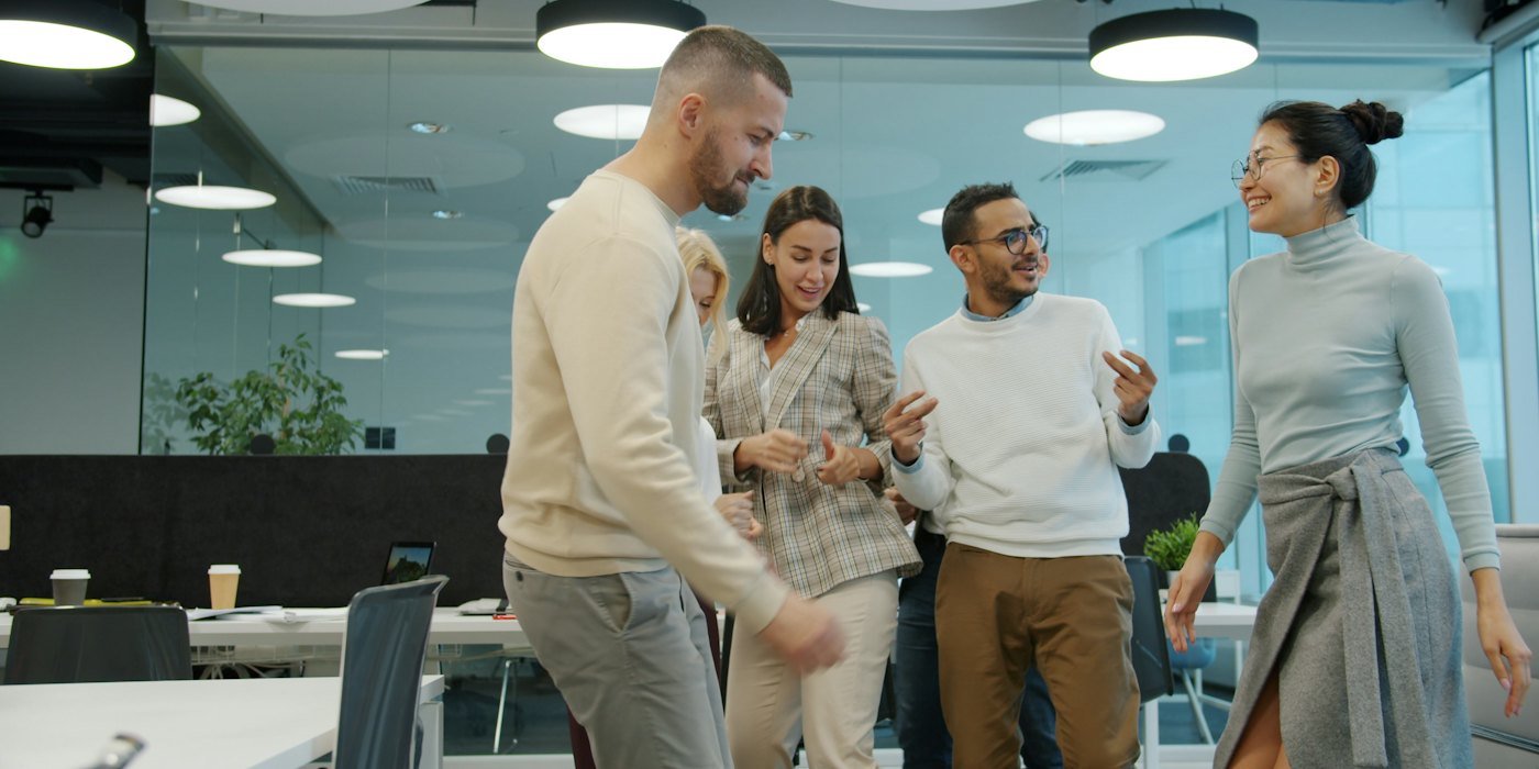 Colegas bailando y celebrando en un entorno de oficina — Cómo comparar dos ofertas de trabajo