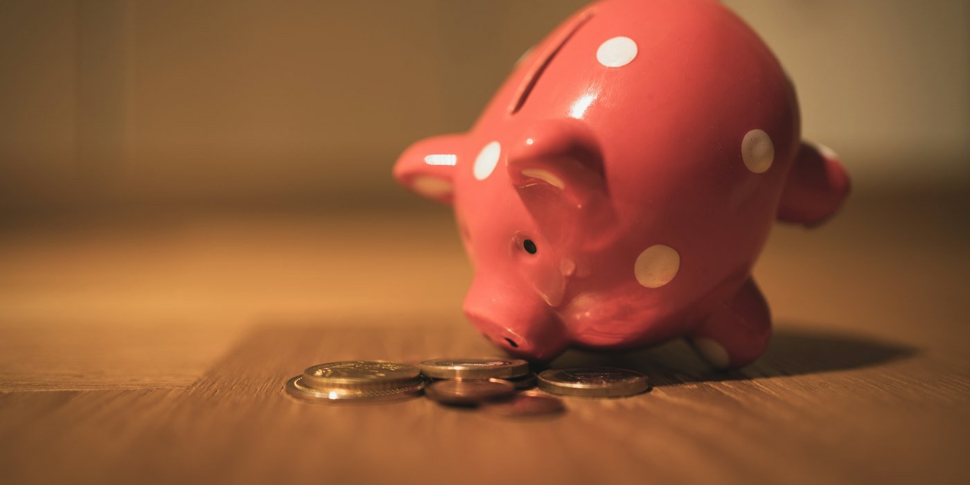 banco de monedas de cerdo rosa sobre mesa de madera marrón — Cómo empezar a ahorrar cuando nunca lo has hecho