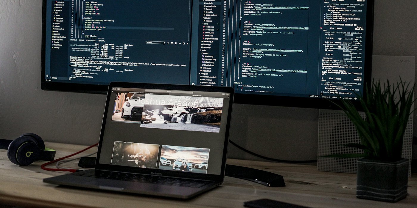 Un portátil y un monitor ancho que mostraba líneas de código en un escritorio — Cómo escribir tu plan de inversión personal