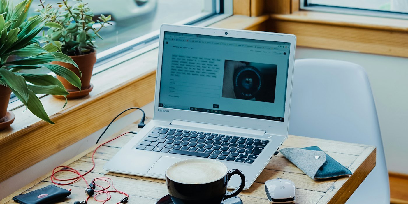 taza de café, computadora portátil y auriculares rojos conectados a la computadora portáti — Cómo ganar más dinero siendo joven: guía realista