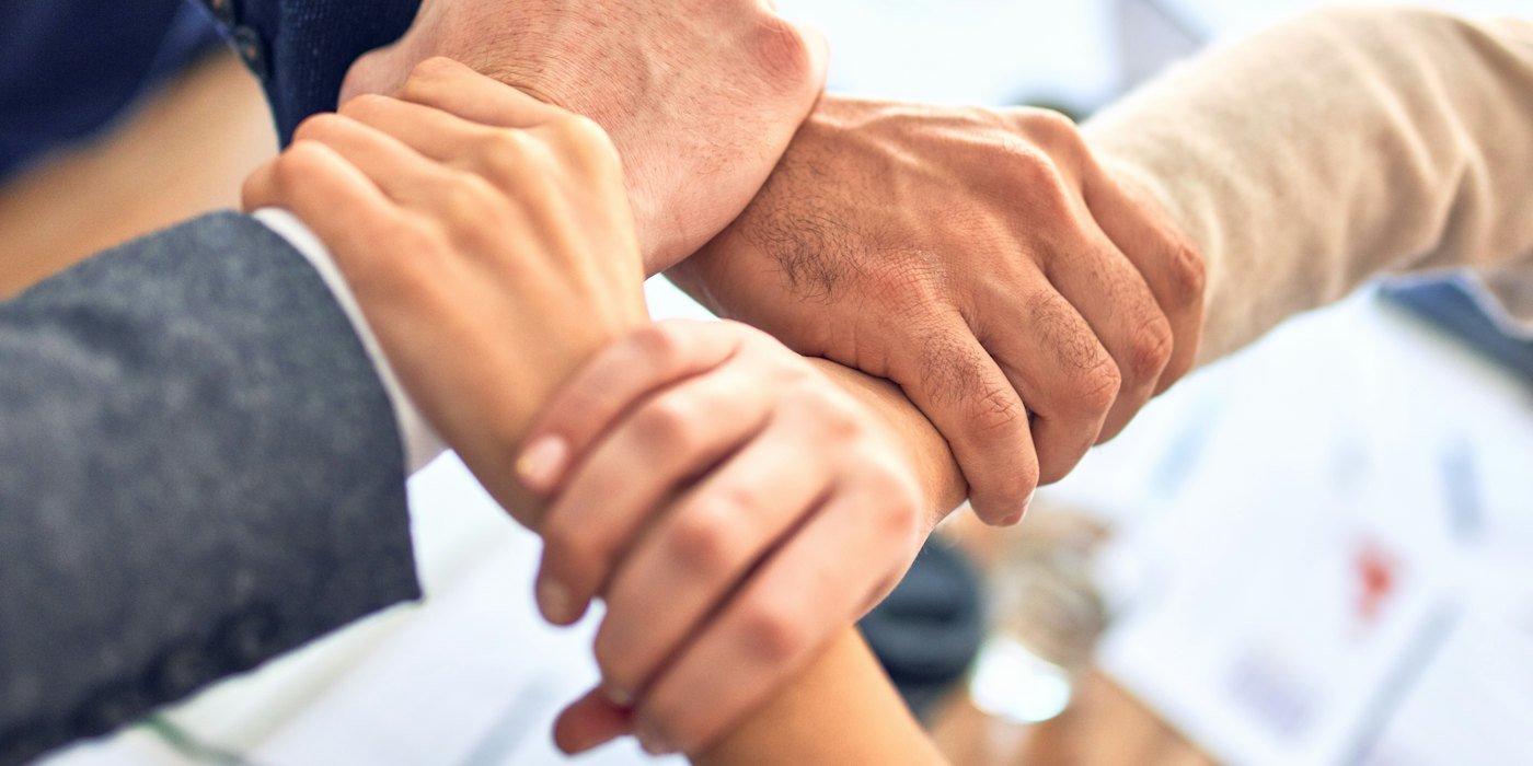 Los miembros del equipo se agarran las muñecas en señal de unidad, gestos — Cómo hacer un currículum que consiga entrevistas