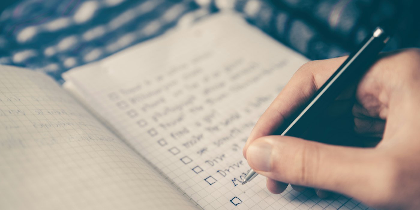 persona escribiendo la lista de deseos en el libro — Cómo hacer un presupuesto mensual paso a paso