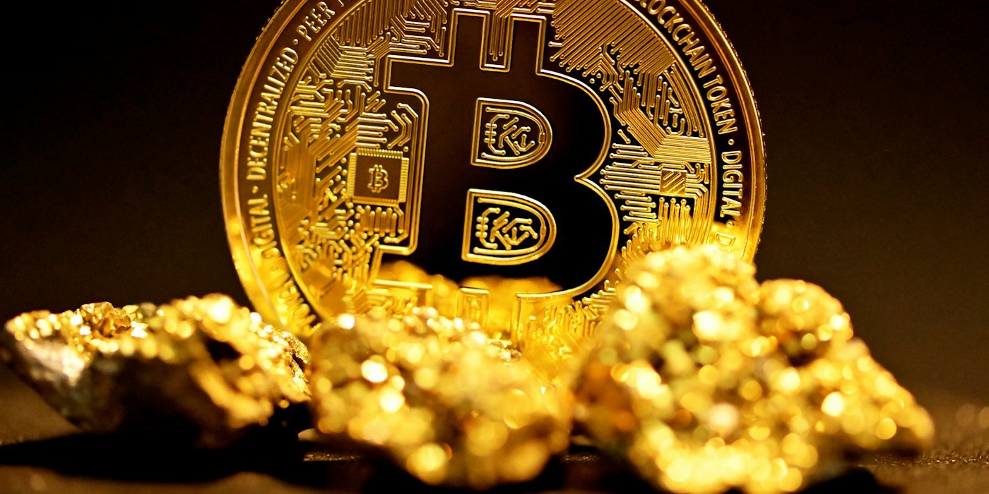 Un bitcoin sentado encima de una pila de pepitas de oro — Criptomonedas desde cero: qué son y qué riesgos tienen