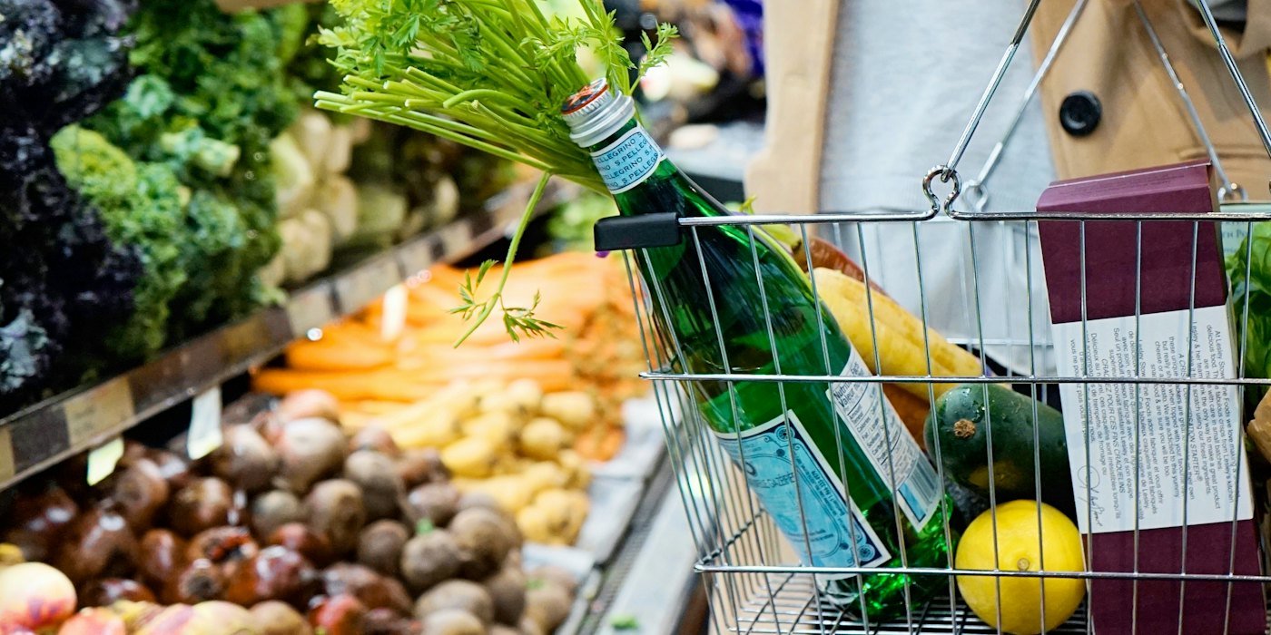 Mujer en bata blanca sosteniendo carrito de compras verde — Cuánto cuesta tener una mascota al año