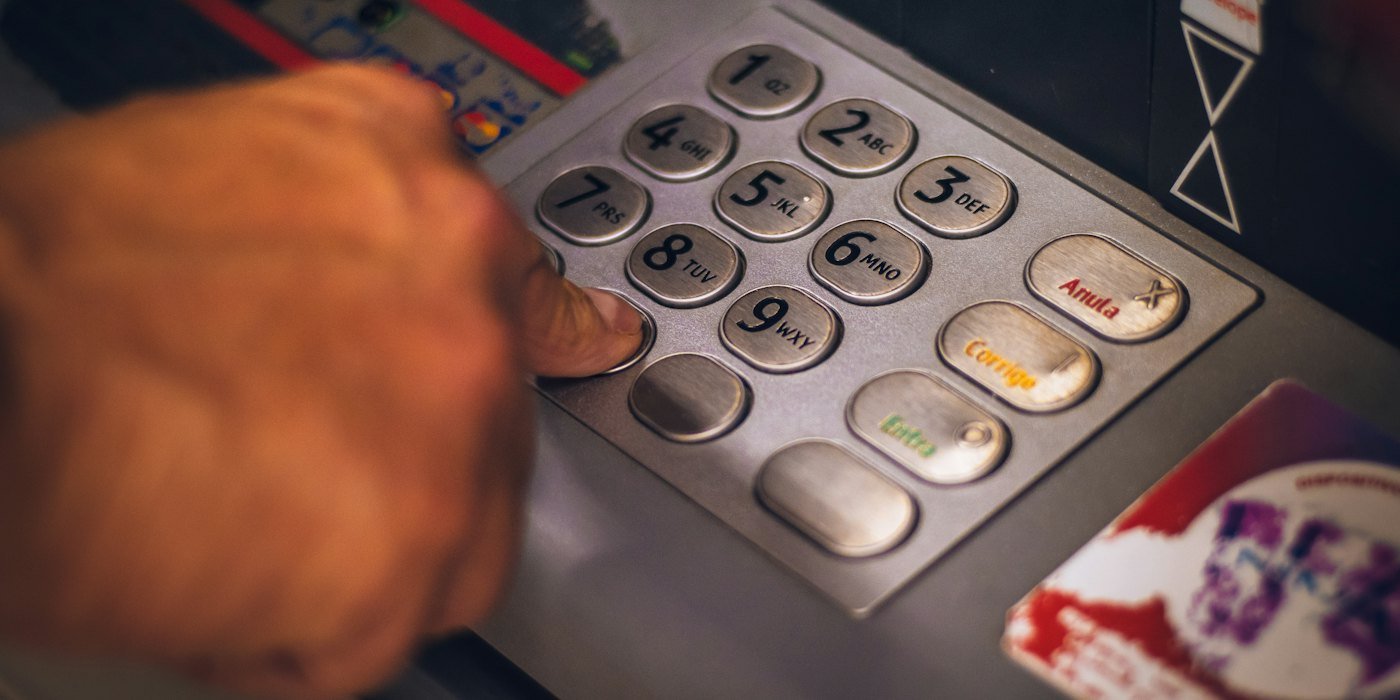 Una persona pulsando un botón en un teclado metálico de un cajero automático — Cuentas para jóvenes: qué ofrecen y qué mirar