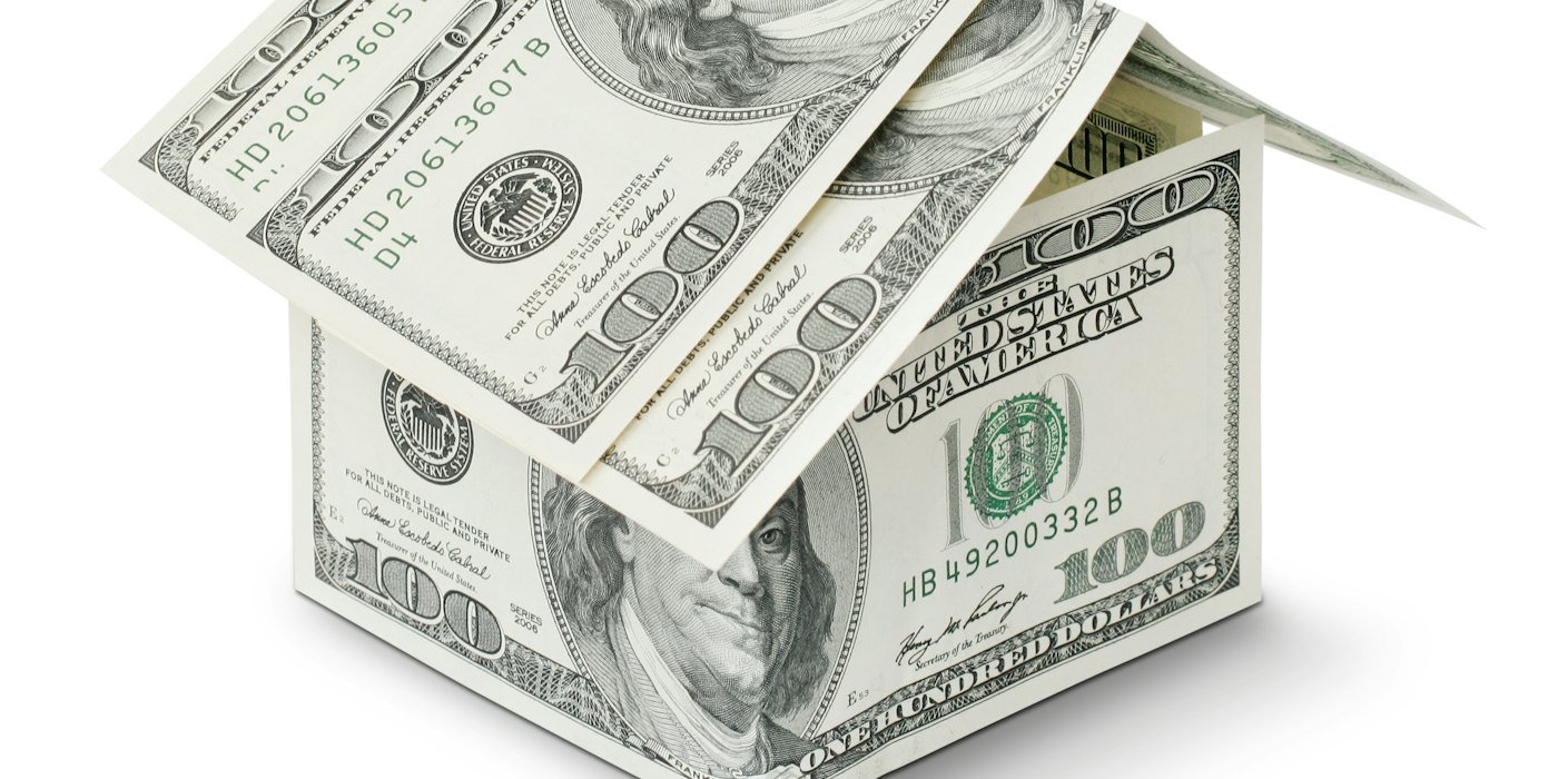 Una casa hecha de dinero sobre un fondo blanco — Descubiertos en cuenta: qué son y cuánto cuestan