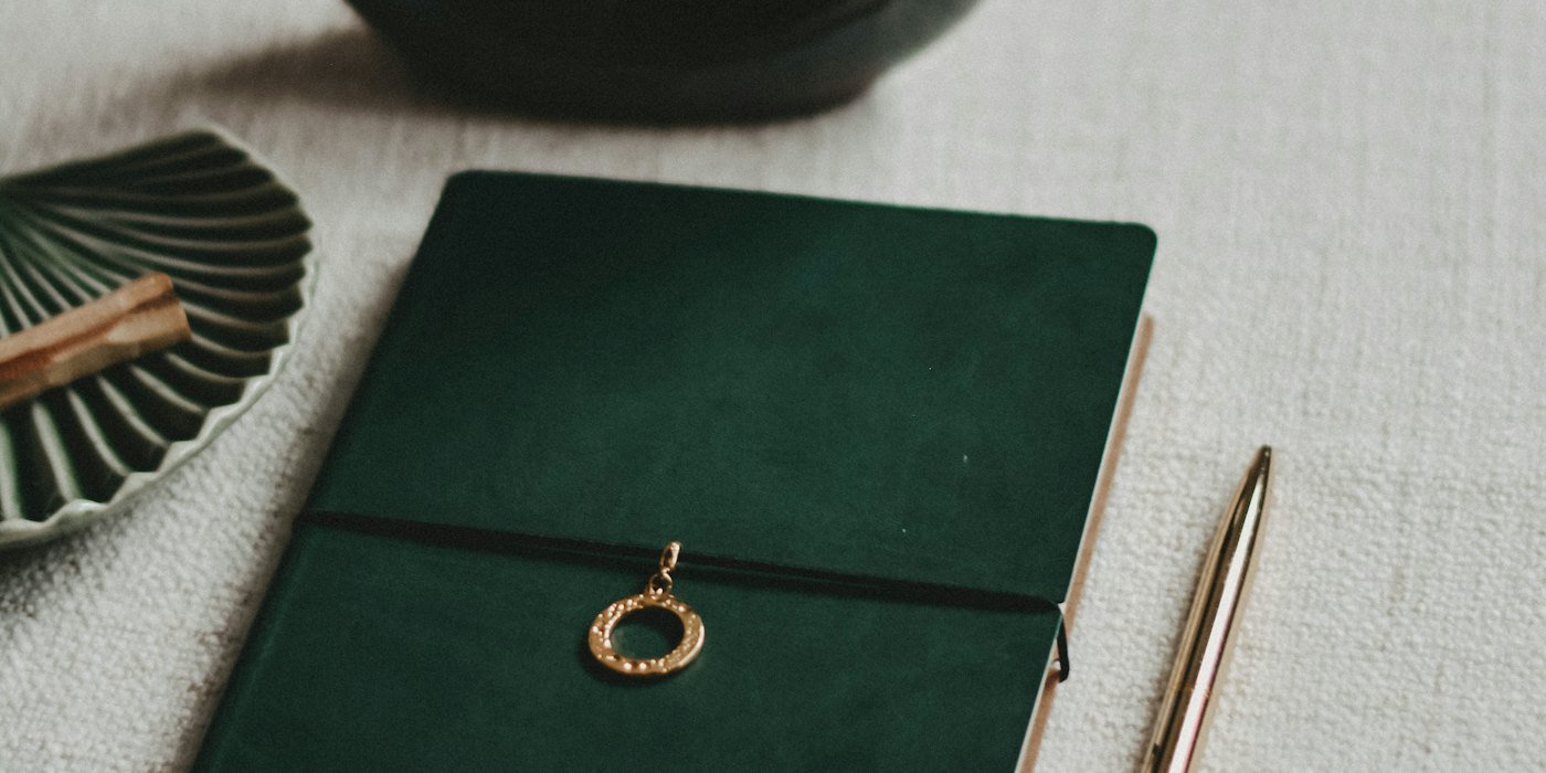 Anillo redondo negro y plateado sobre libro verde — Disciplina financiera sin castigarte