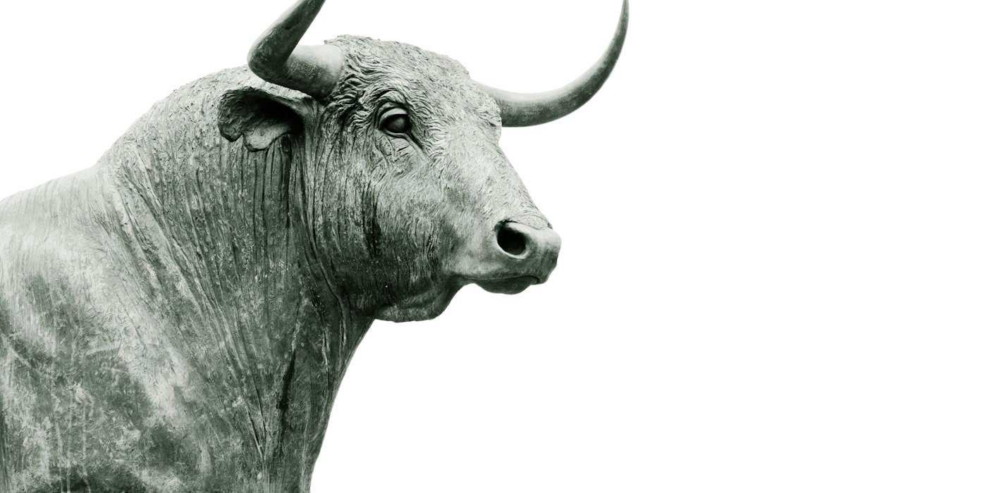 Una estatua de toro de bronce con grandes cuernos sobre un fondo blanco liso — Dividendos: qué son, cómo se cobran y cómo tributan