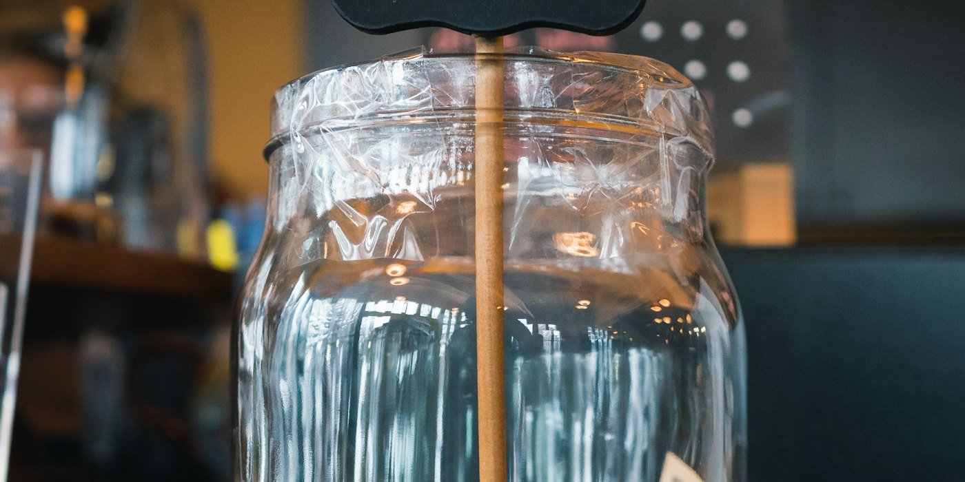Frasco de vidrio transparente sobre mesa de madera marrón — Dónde guardar tu dinero según el plazo
