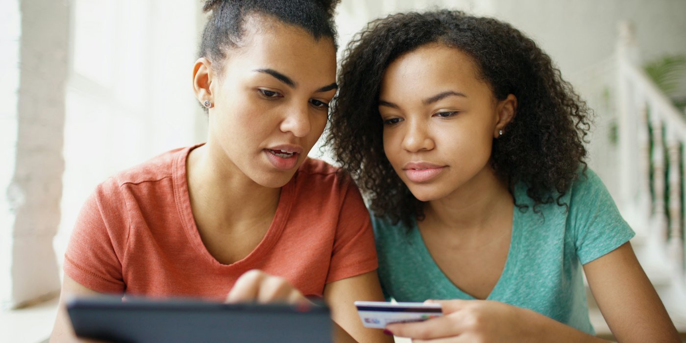 Dos mujeres jóvenes mirando una tableta con tarjeta de crédito — Educación financiera: cómo aprender por tu cuenta sin caer en vendehúmos