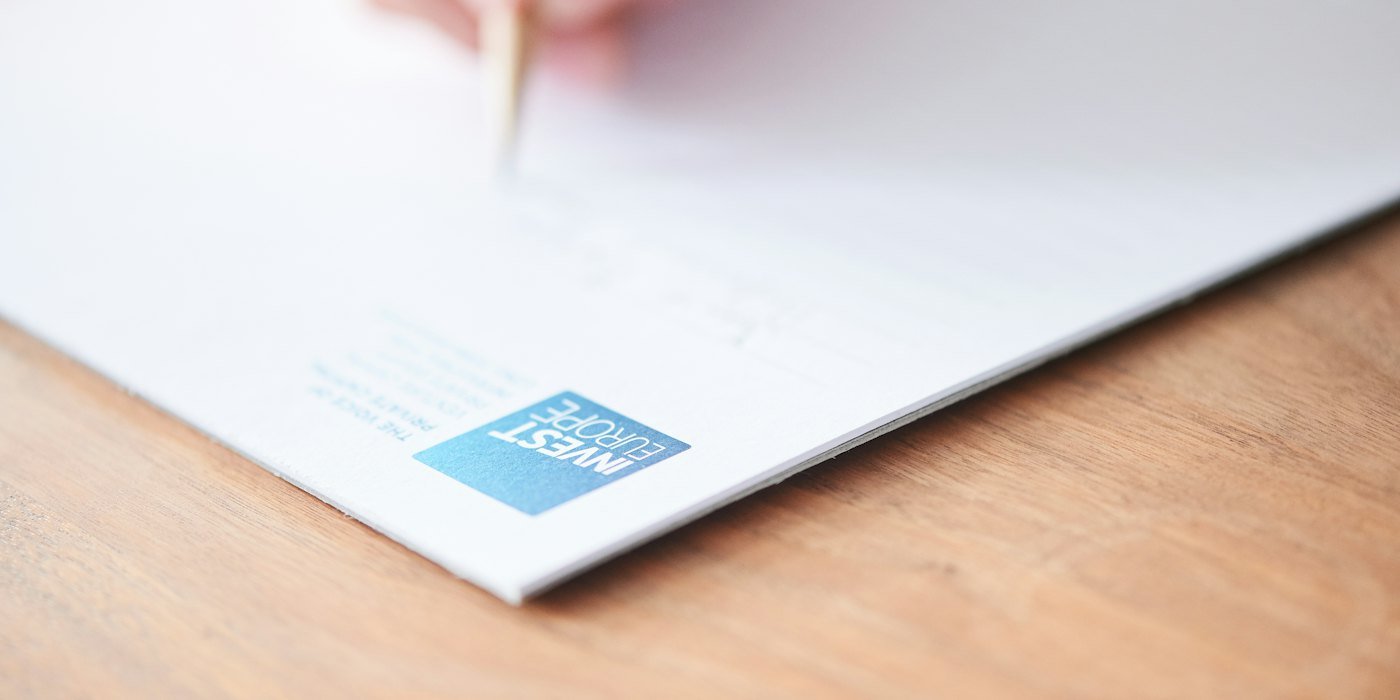 Una mano escribe en papel blanco con un logo azul — Facturar sin ser autónomo: mitos y realidad