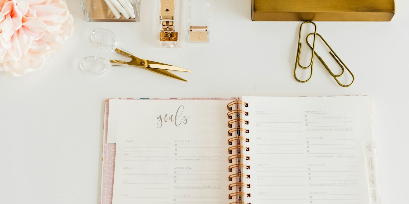 tijeras y dos clips junto al cuaderno de espiral abierto — Gastos hormiga: cómo detectarlos y cuánto te cuestan al año