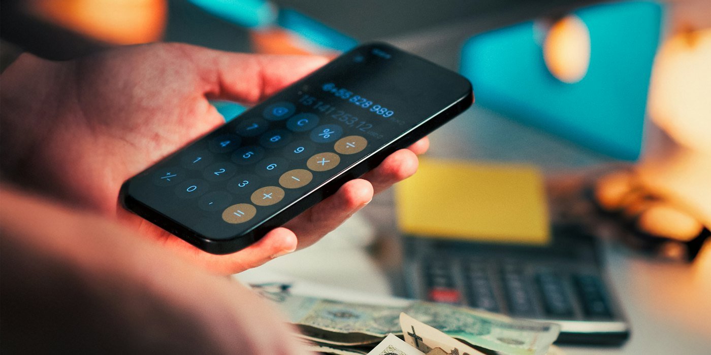 Manos sujetando dinero y usando la calculadora en el móvil — Inflación: por qué tu dinero vale menos cada año