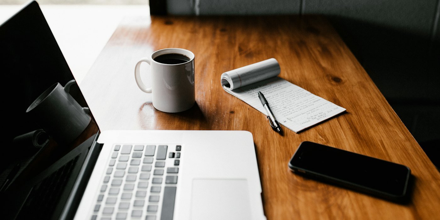 MacBook Pro, white ceramic mug,and black smartphone on table — Ingresos pasivos: mitos y realidades