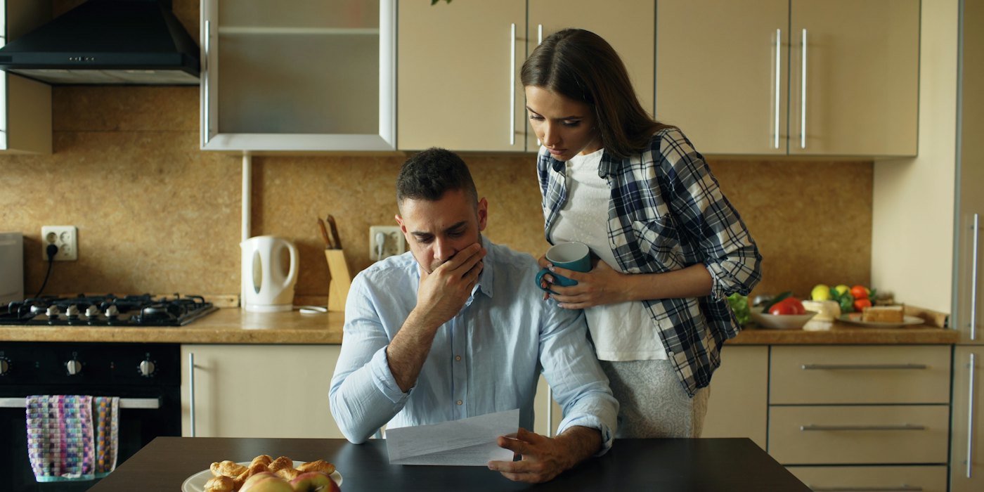 Pareja mirando estresada por las facturas en la mesa de la cocina — Intereses usurarios: qué son y cómo reclamarlos
