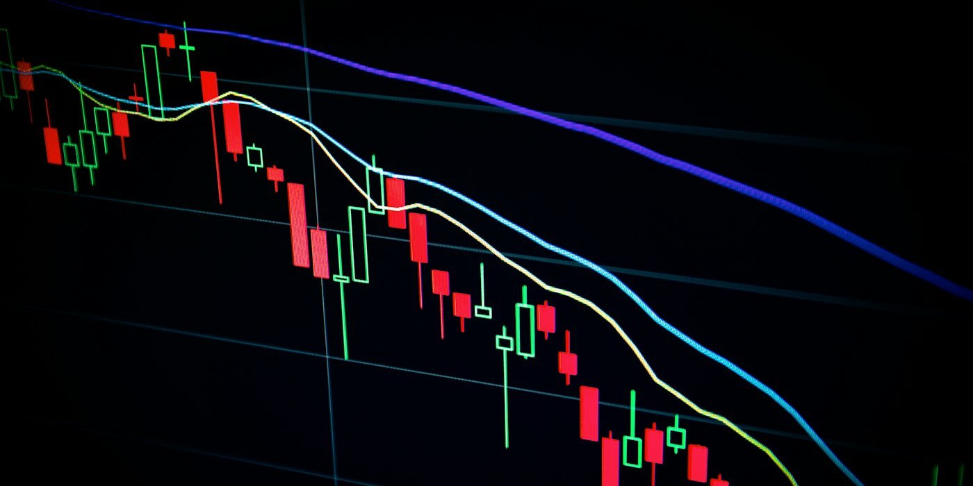 Gráfico de velas del mercado bursátil en pantalla oscura — Invertir desde cero: guía completa para jóvenes