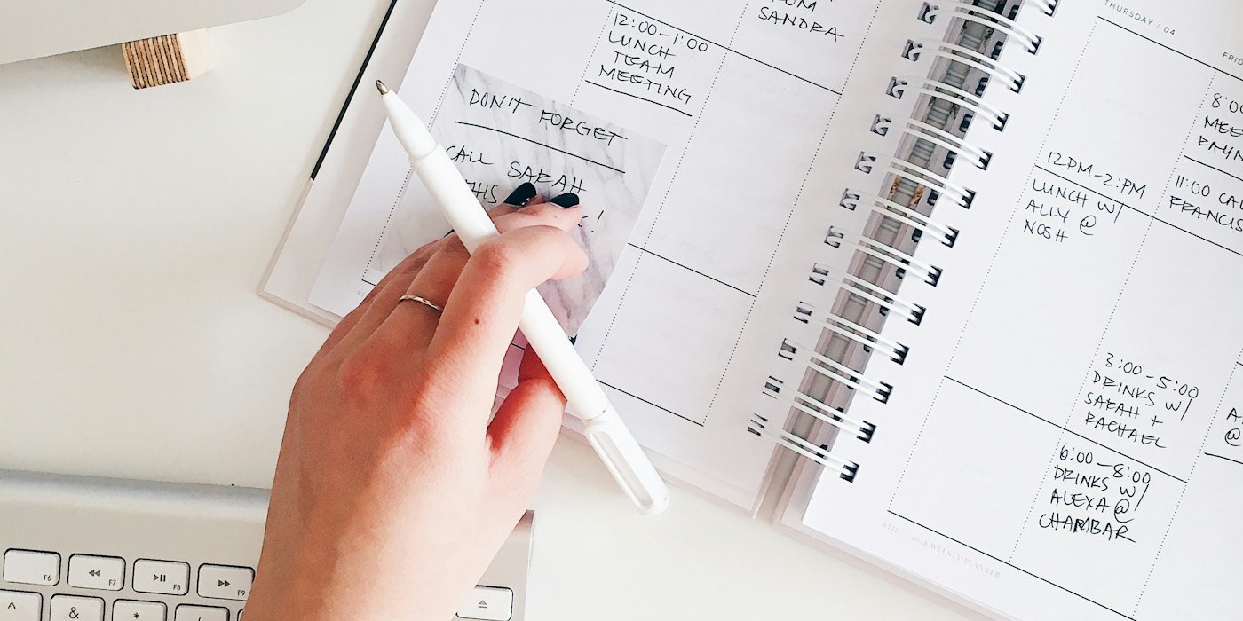 person holding notepad and pen flat lay photography — La regla 50/30/20 explicada con ejemplos reales