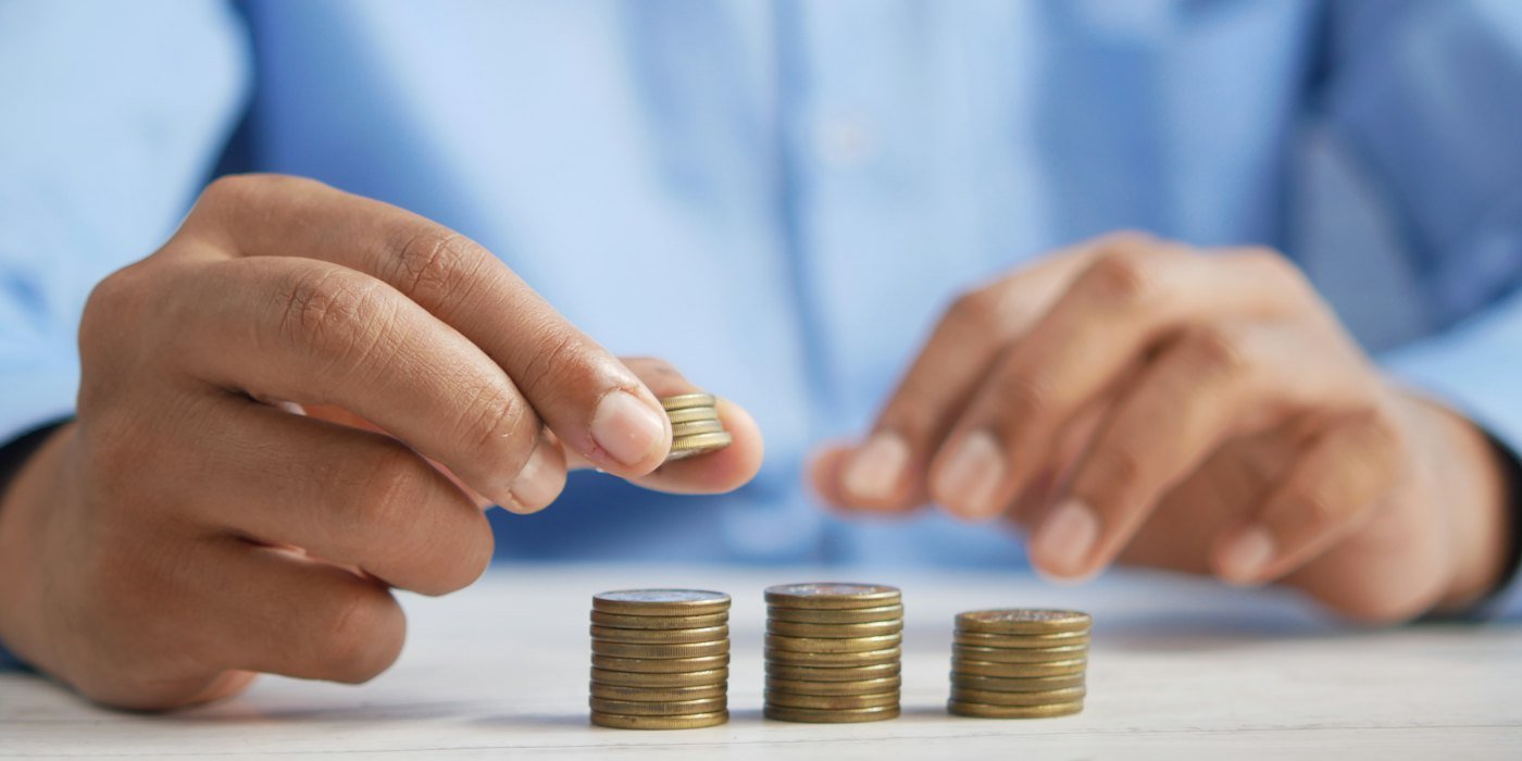 Una persona apilando monedas encima de una mesa — Los errores de dinero más comunes antes de los 30