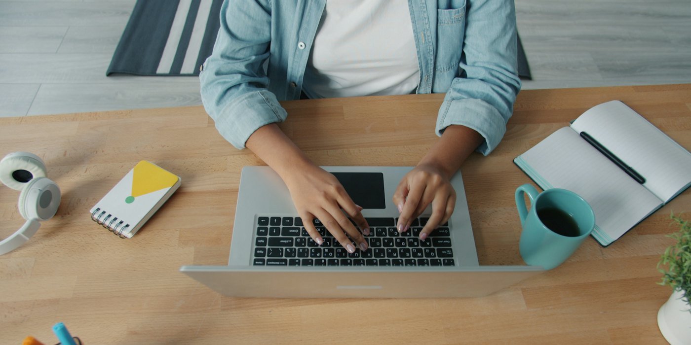Persona escribiendo en una computadora portátil en un escritorio de madera — Marketing de afiliación: qué es y cómo funciona
