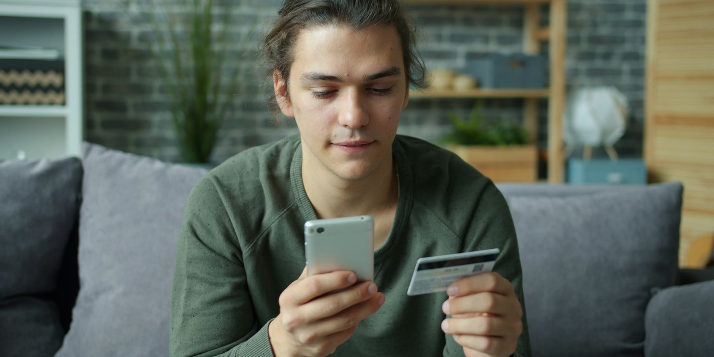 Joven que usa teléfono inteligente y tarjeta de crédito para compras en línea — Objetivos financieros SMART: cómo plantear metas que se cumplen