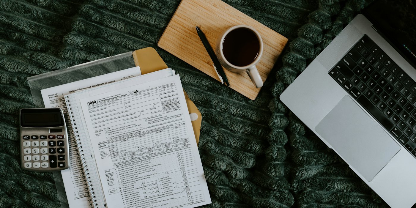 Portátil, papeles, calculadora y café sobre una manta — Presupuesto base cero: cómo asignar cada euro