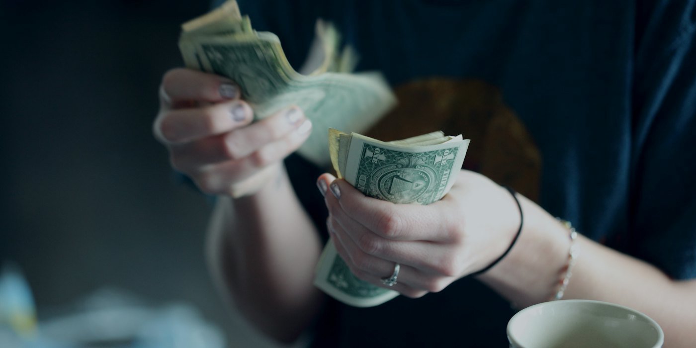 Fotografía de enfoque de persona contando billetes de dólar — Qué es la libertad financiera y cómo calcular tu número
