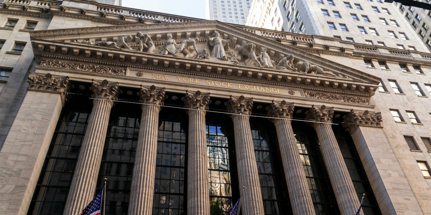 Edificio de la Bolsa de Nueva York con banderas americanas — Qué es una acción y por qué sube o baja de precio