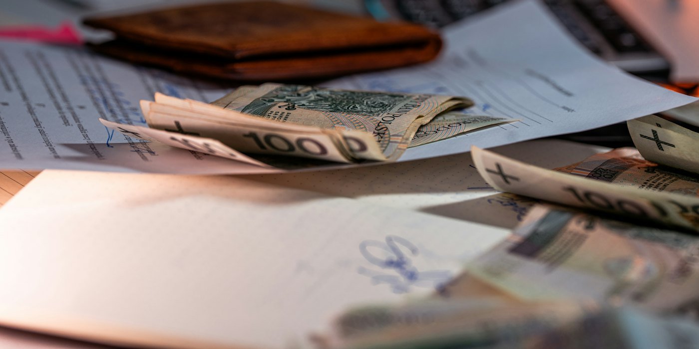Dinero y documentos sobre un escritorio — Qué hacer cuando te sales del presupuesto