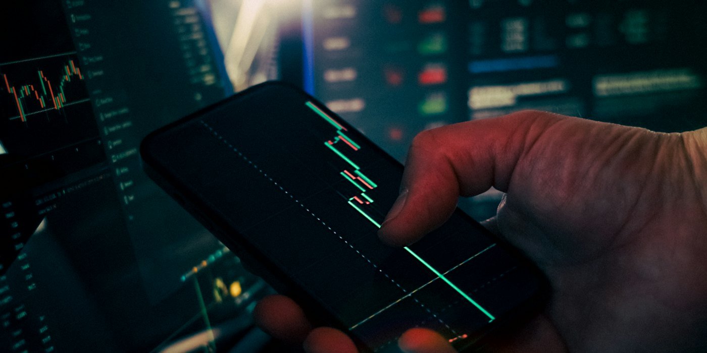 Trader analizando datos del mercado de valores en teléfonos inteligentes y teléfonos — Rentabilidad histórica: qué nos dice y qué no