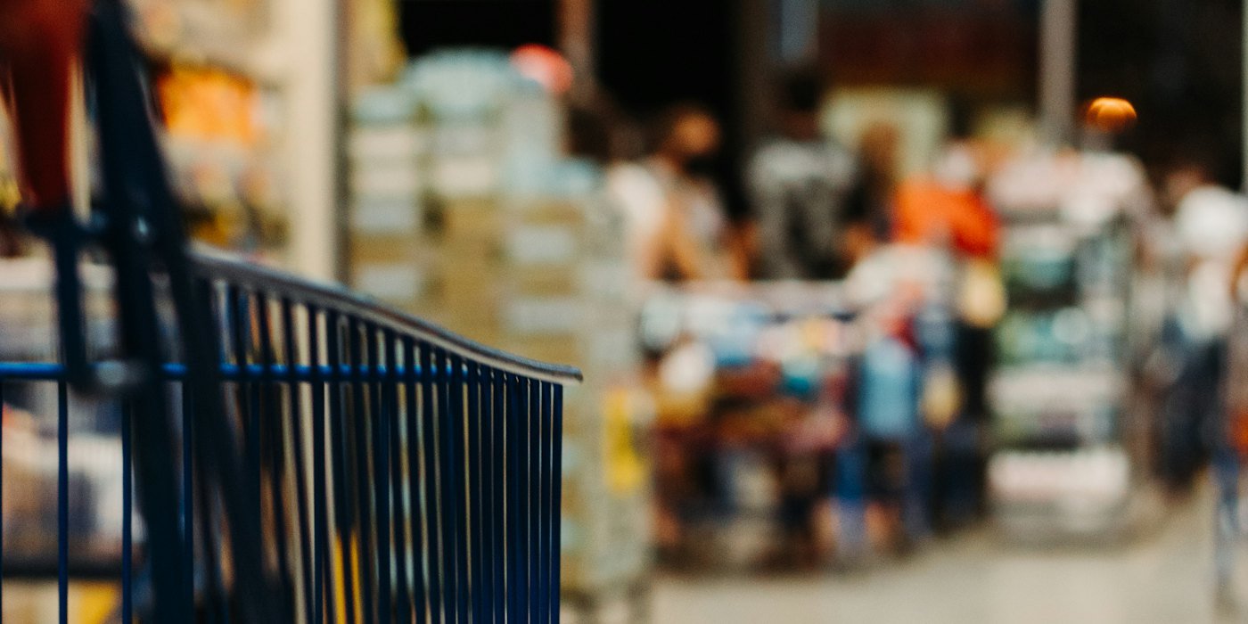 Un carrito de la compra azul en un pasillo borroso del supermercado — Revisión trimestral del presupuesto: qué mirar y cómo ajustar