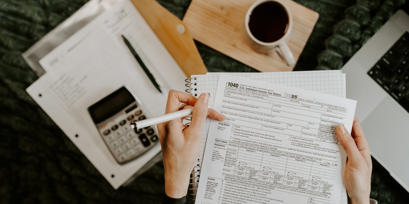 Persona revisando documentos con calculadora y portátil — Tu primer año de finanzas: calendario mes a mes